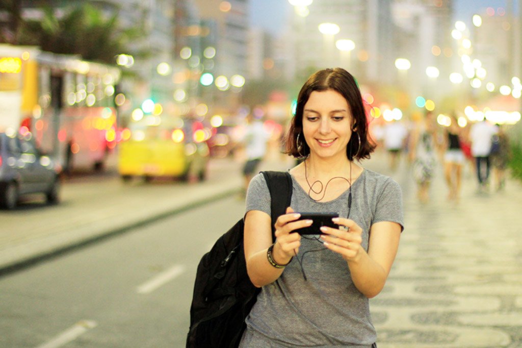 Mulher usando smartphone na Orla de Copacabana | Marketing digital: crescimento mobile no Brasil